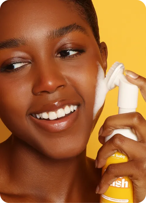 Sugar Baby skincare model using a facial cleansing brush