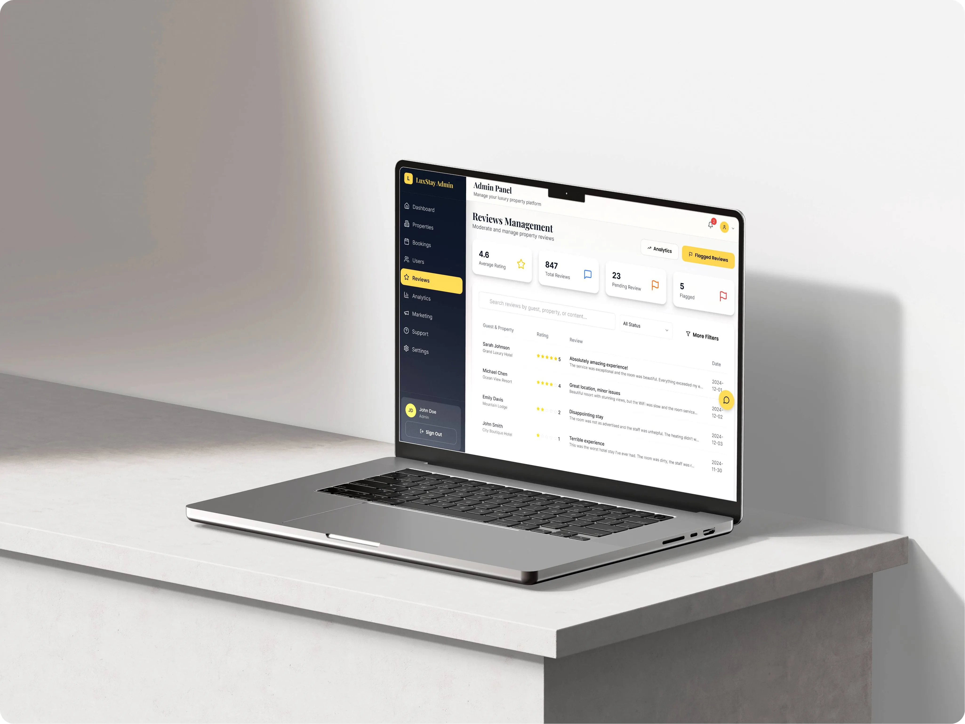 Laptop showing the LuxStay reviews management screen with average rating, pending and flagged reviews and a list of guest reviews