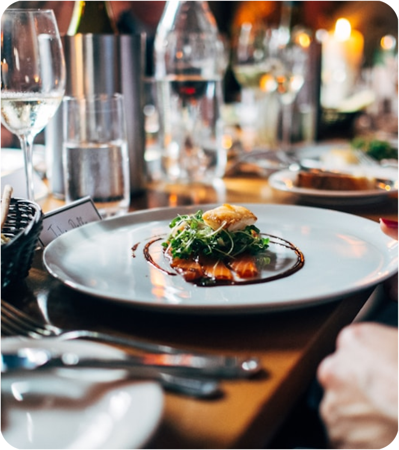 Gourmet fish dish with microgreens plated on a candlelit fine-dining table
