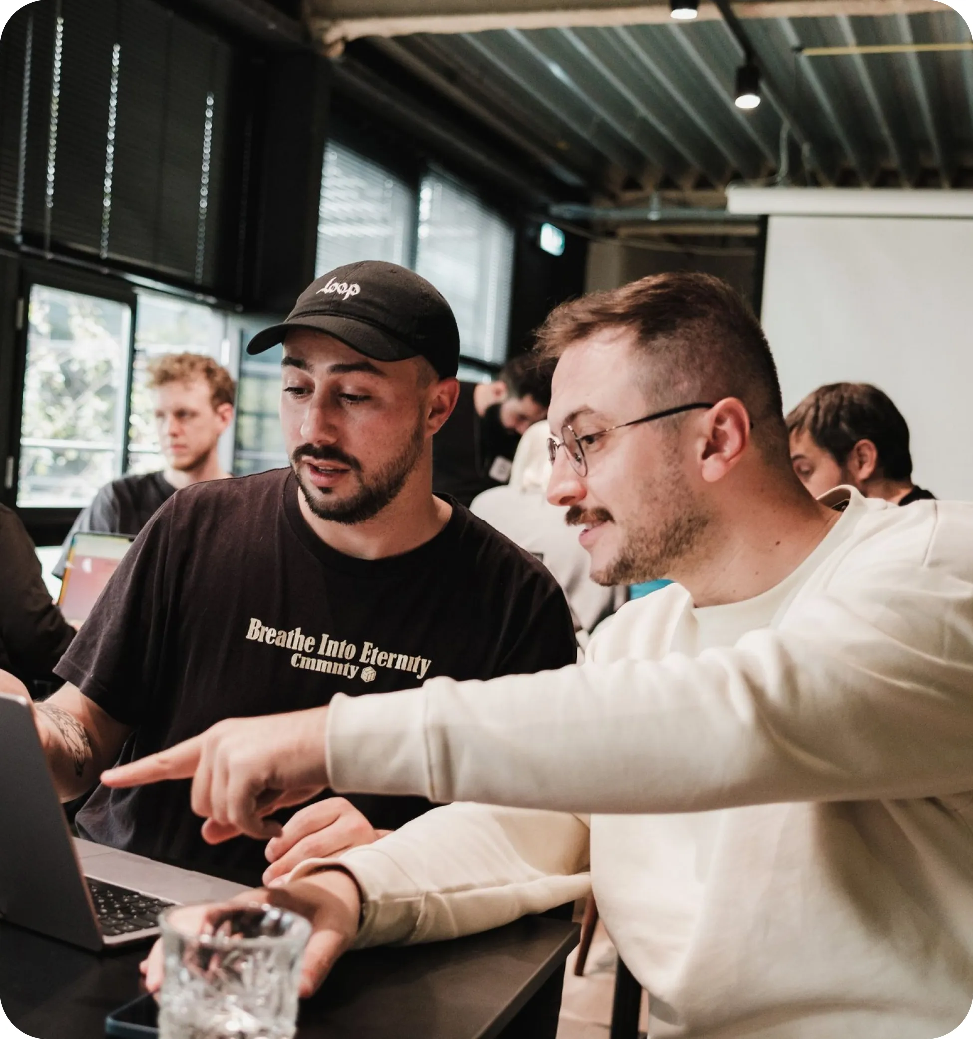 Two team members reviewing work together on a laptop in a shared office