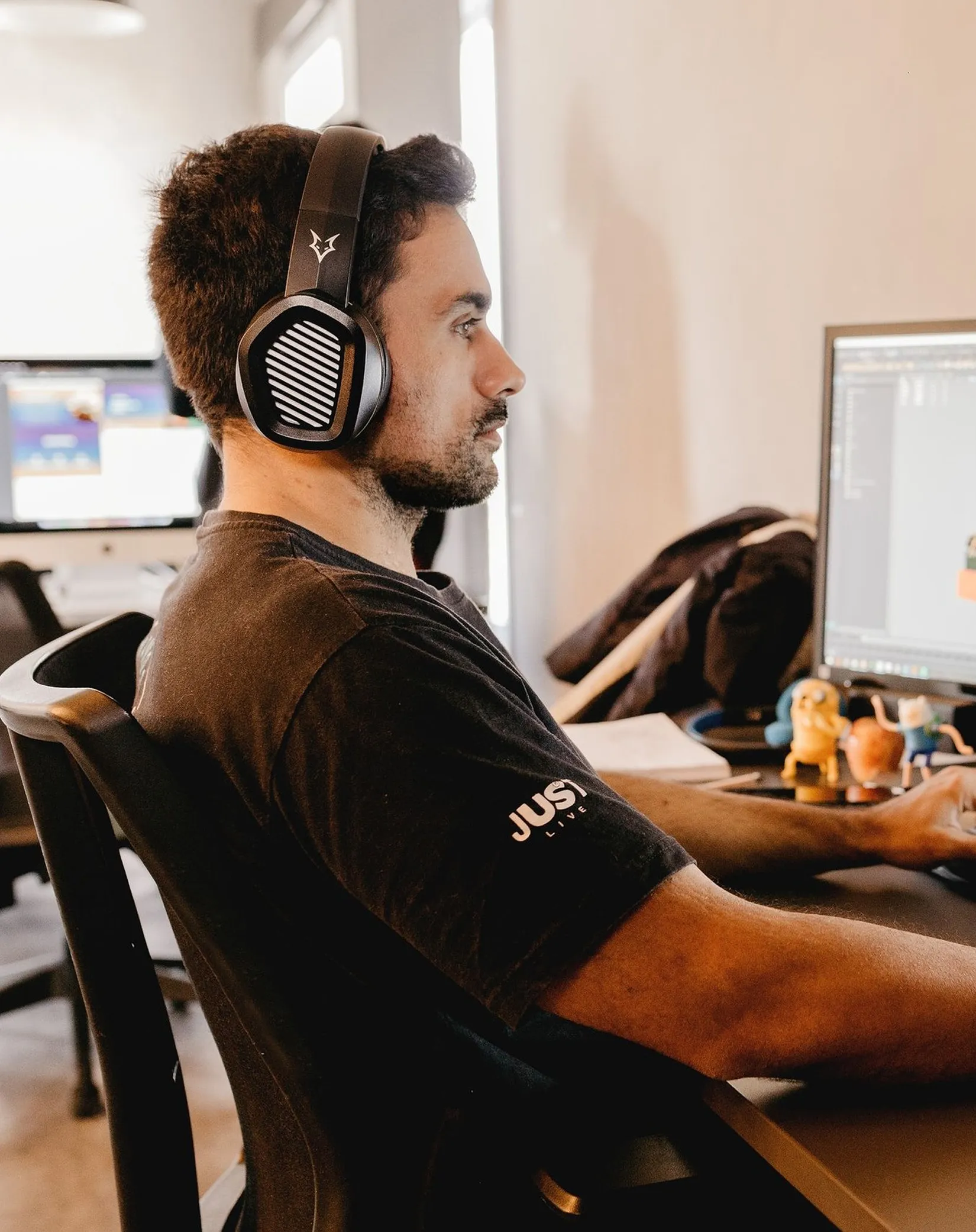 Developer wearing headphones working at a desktop computer in a studio