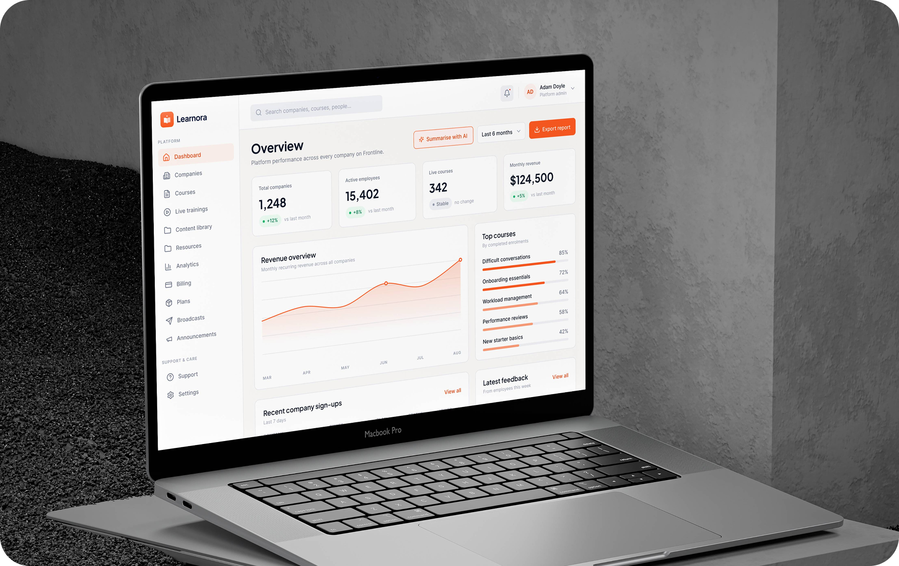 Learnora training platform overview dashboard with revenue chart, top courses, and recent company sign-ups on a laptop