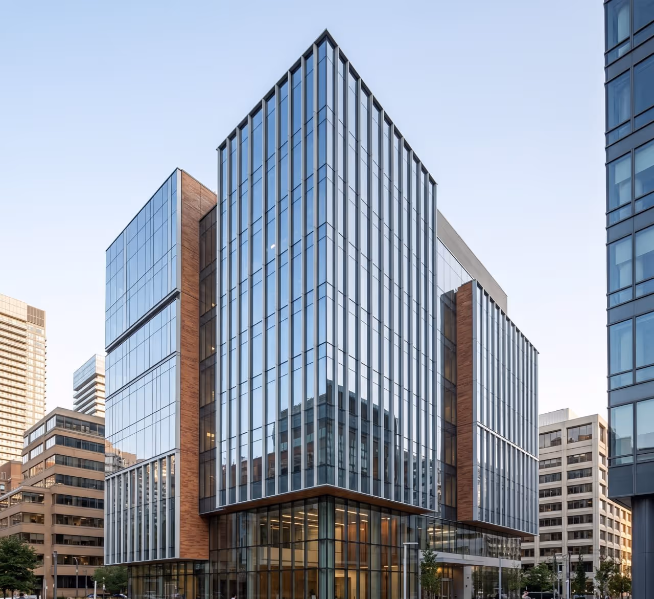 Modern office building with glass facade and brick accents in an urban setting.