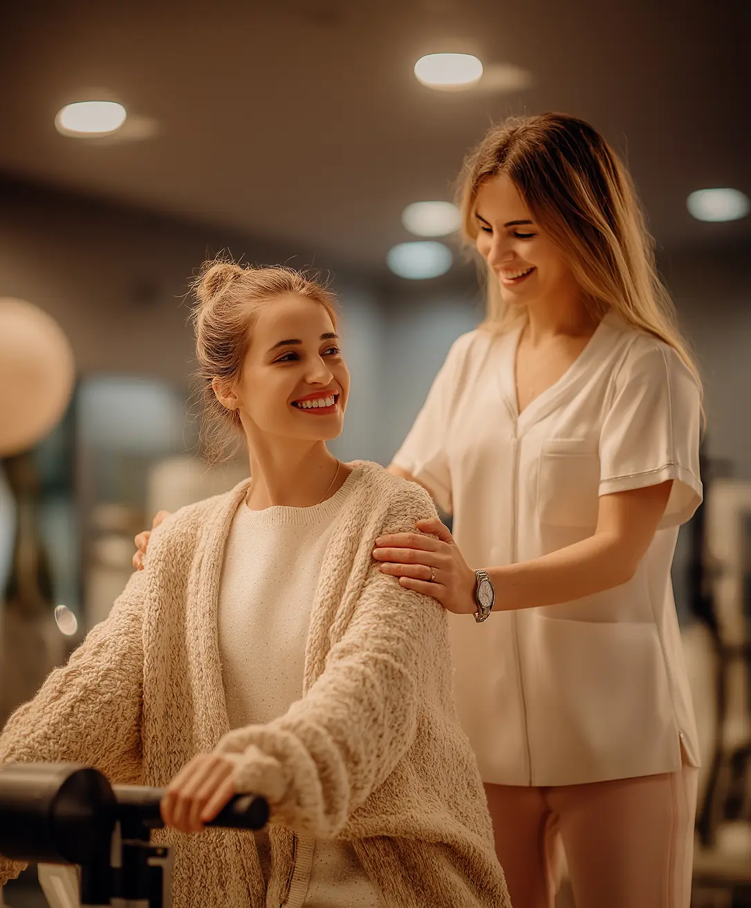 A smiling physical therapist assisting a female patient on an exercise machine.