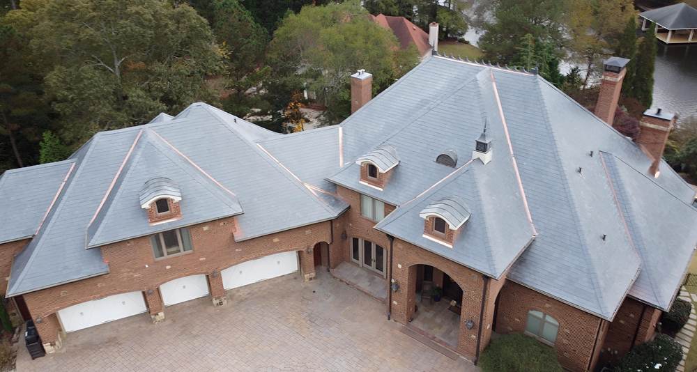 Front aerial of a brick estate with a composite slate roof