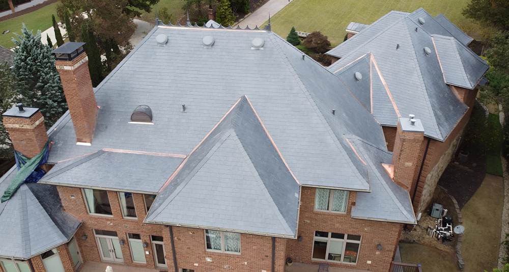 Aerial of a brick home with a light gray composite slate roof