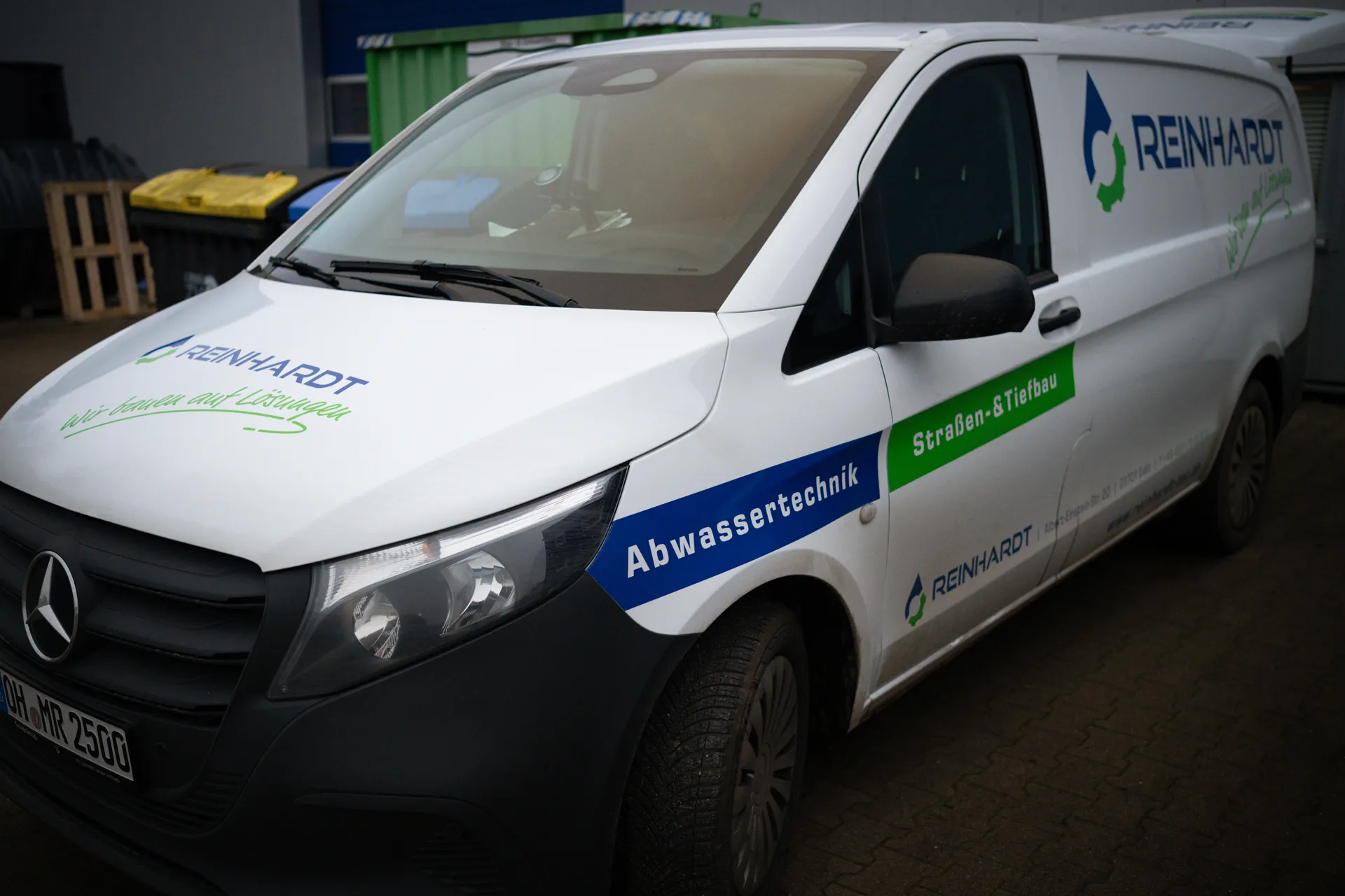 Weißer Transporter mit Beschriftung der Firma Reinhardt, spezialisiert auf Abwassertechnik und Straßen- & Tiefbau.