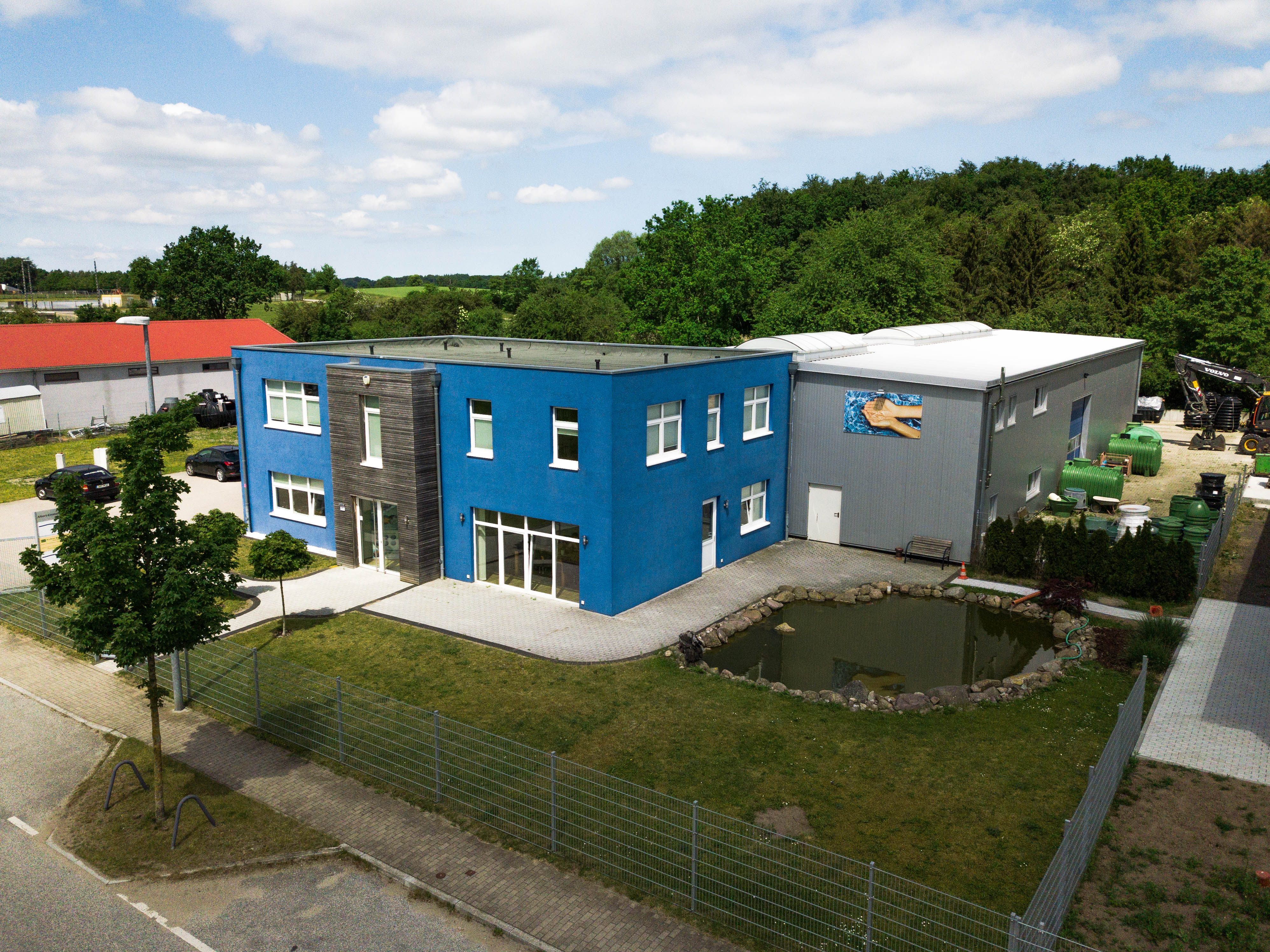 Zwei Bauarbeiter mit reflektierender Arbeitskleidung, die bei einer Straßenbaustelle auf einem Bürgersteig arbeiten.