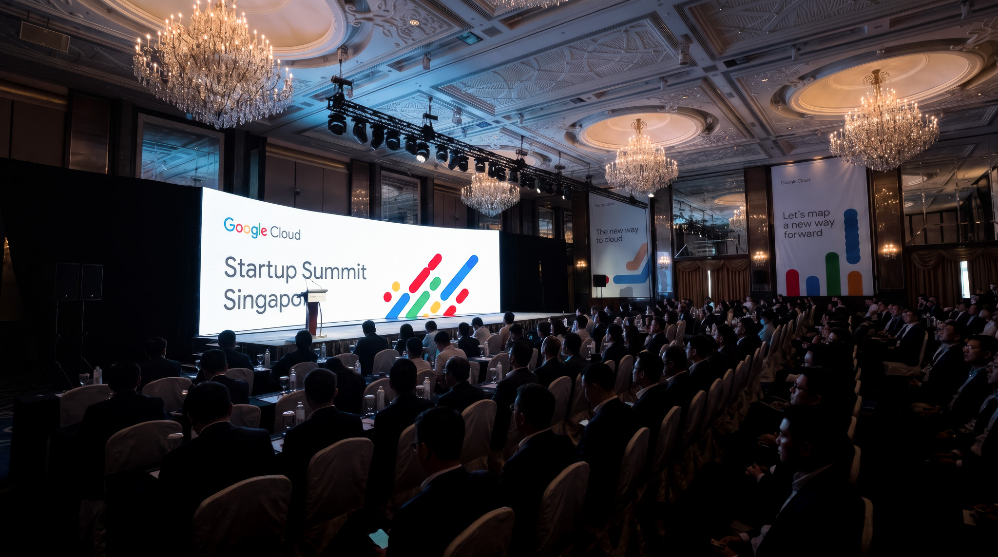 Google Cloud Startup Summit Singapore in a hotel ballroom, with the audience facing a curved stage screen
