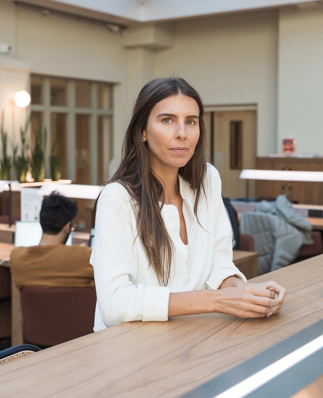 Une photo portrait de la fondatrice de POLI, Juliette Portos, qui pose en regardant l'objectif et avec les mains posées sur un rebord en bois