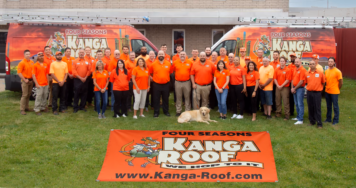 Man in orange polo stands with arms crossed in front of an orange service van with company branding.
