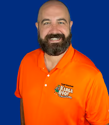 Smiling bald man with beard wearing an orange Kanga Roof polo shirt on blue background.