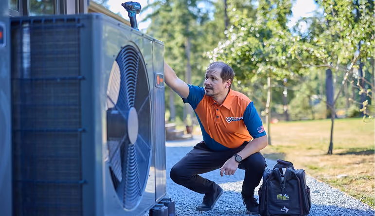 Technician carrying tools walking beside a blue Baker Brothers service van outside a residential home.