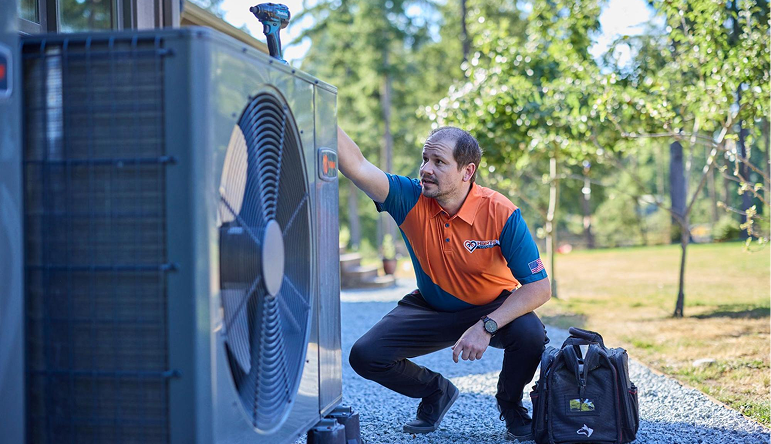 Technician carrying tools walking beside a blue Baker Brothers service van outside a residential home.