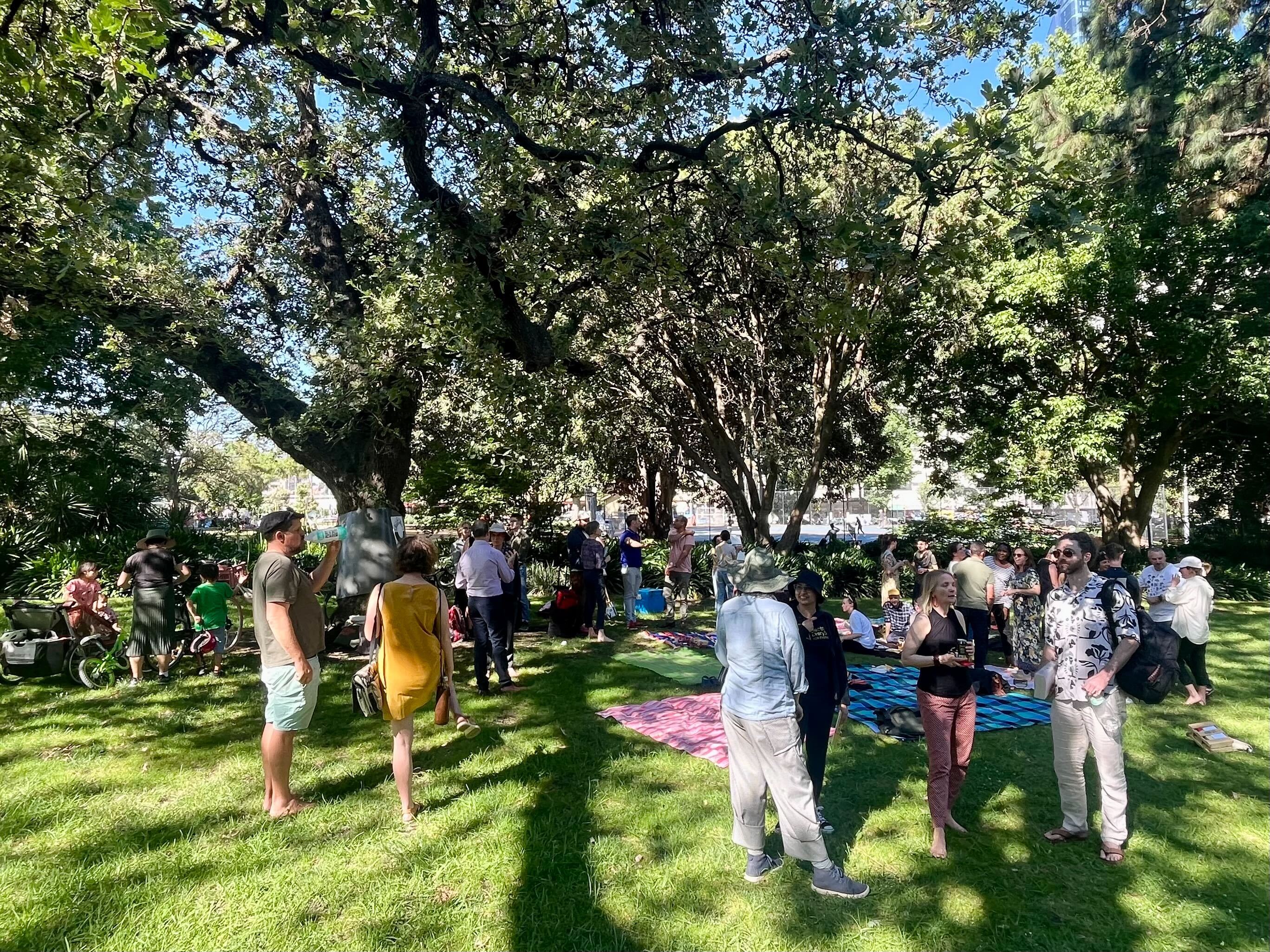 Community picnic gathering under large trees in a Melbourne park
