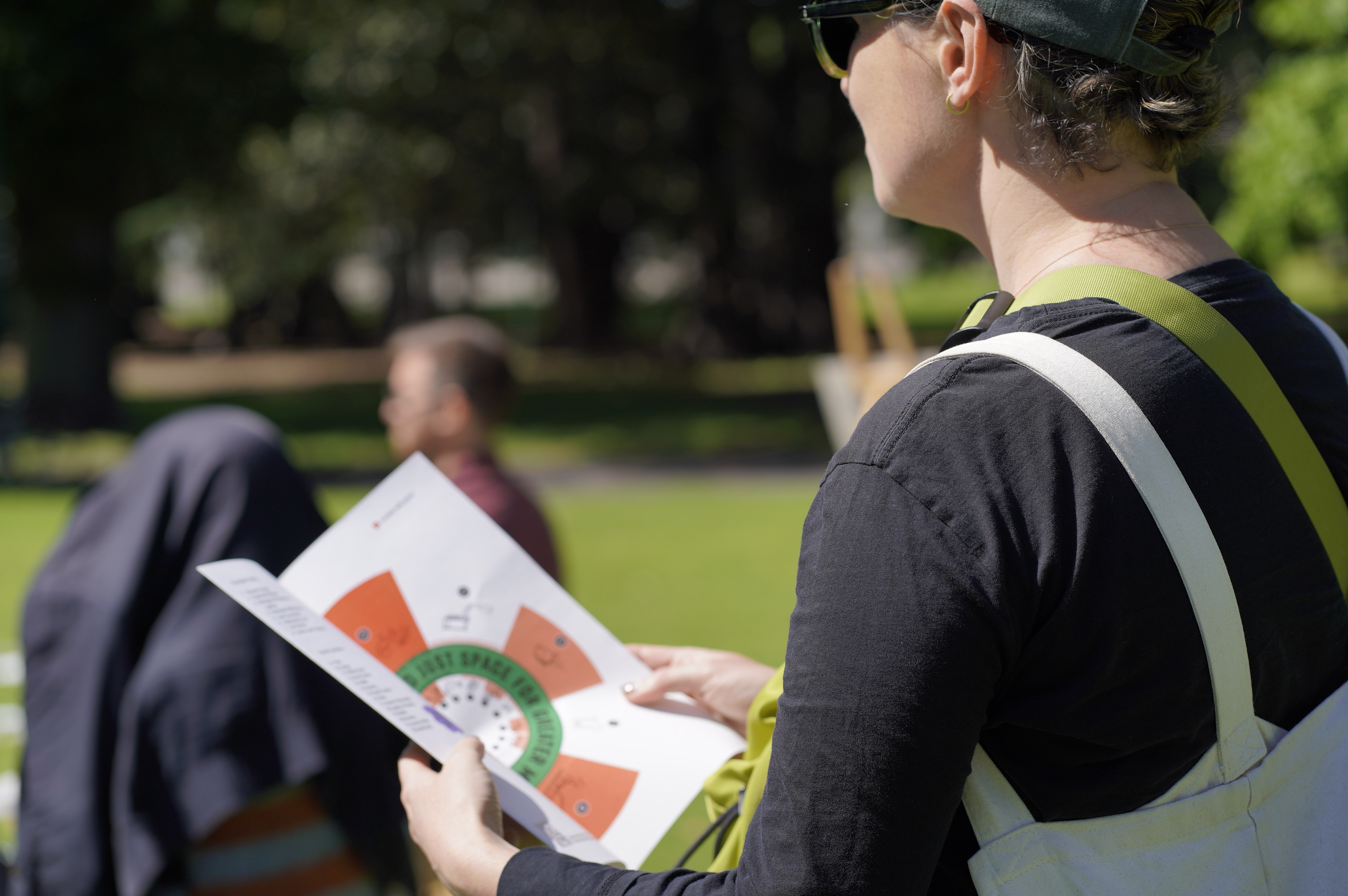 Participant reading the City Portrait doughnut diagram booklet at an outdoor park event