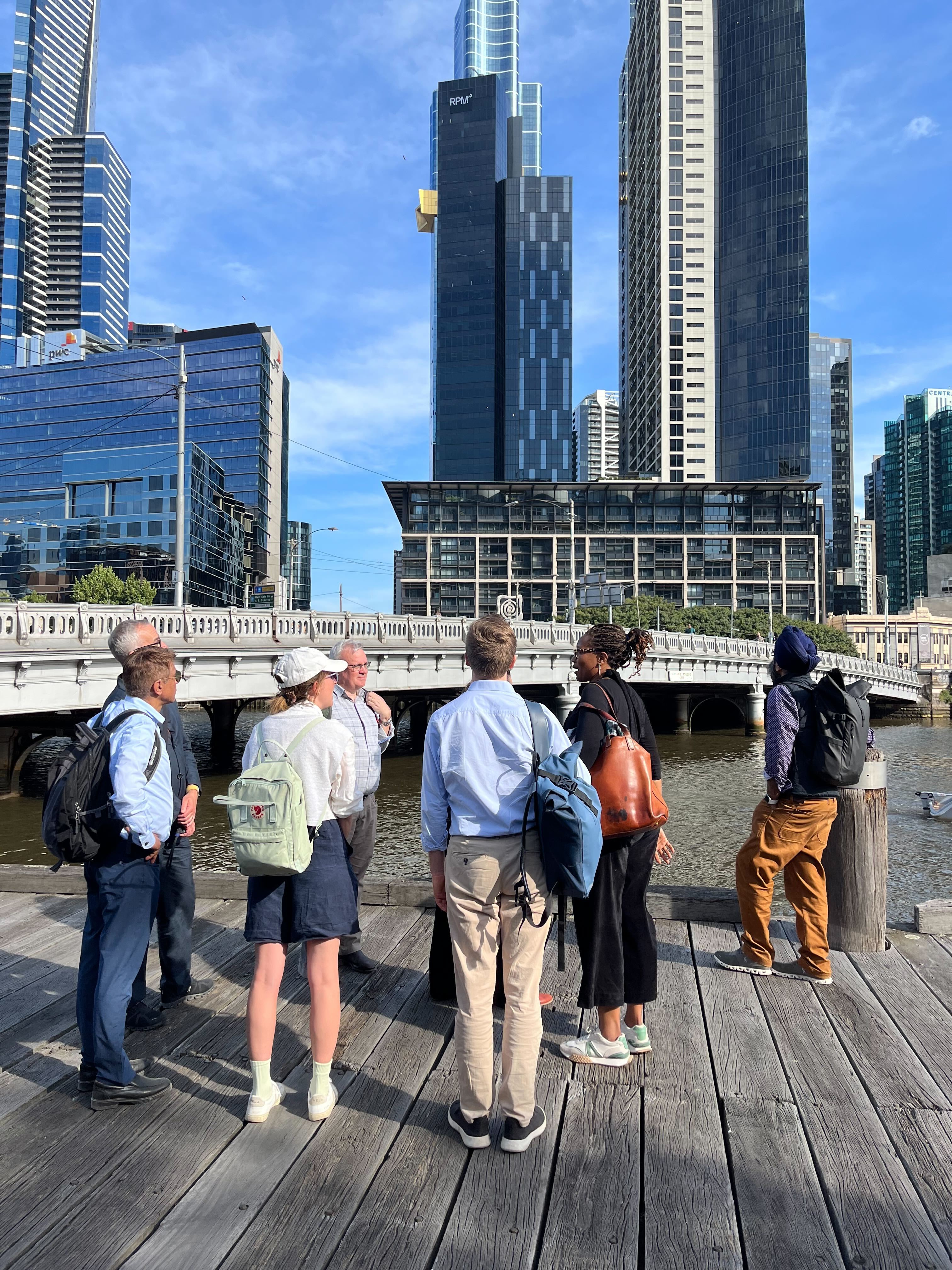 Group standing on Southbank boardwalk looking at Melbourne skyline and the Birrarung