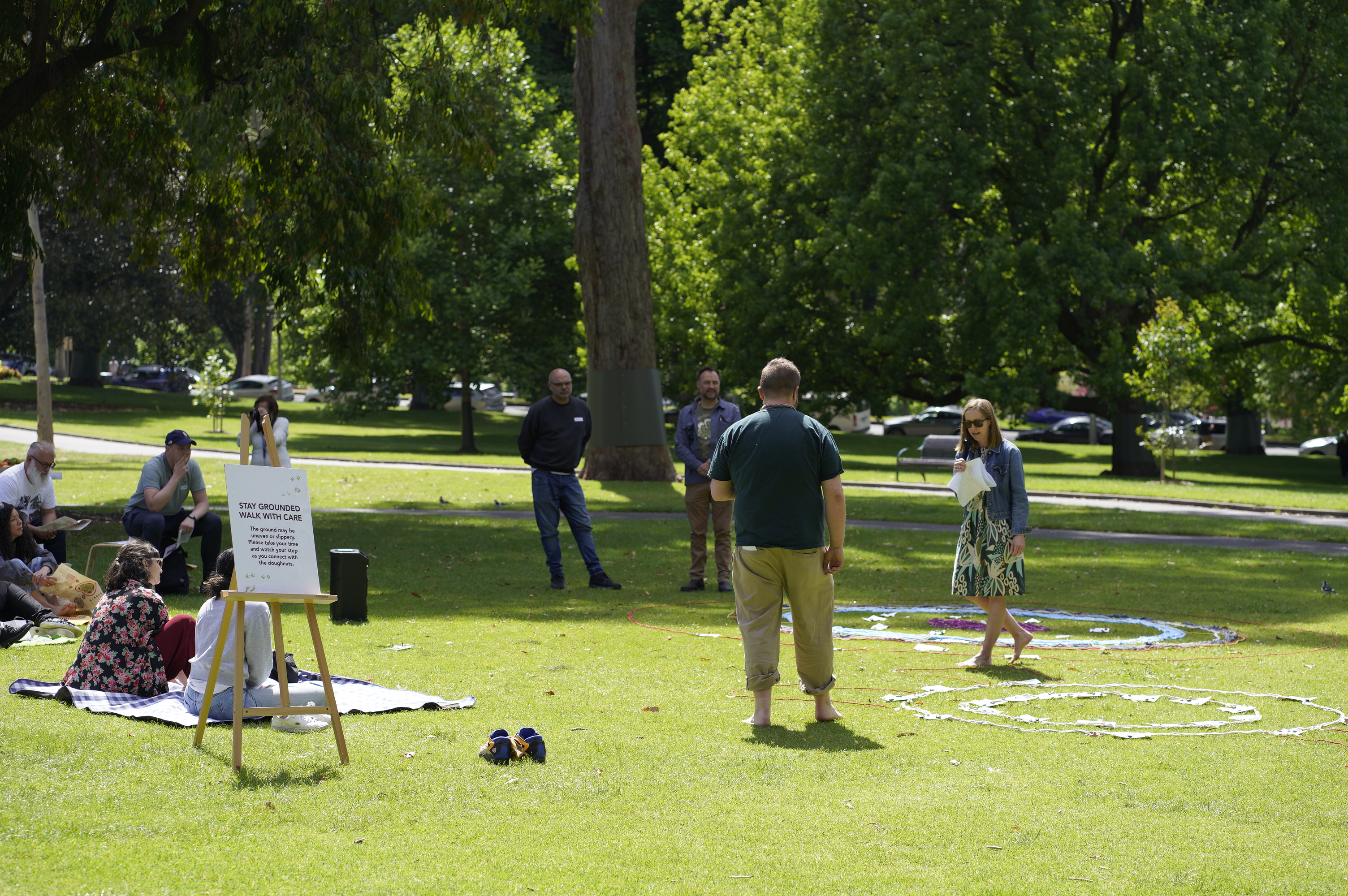 Facilitators near a Stay Grounded Walk with Care sign at a Regen Melbourne park activation