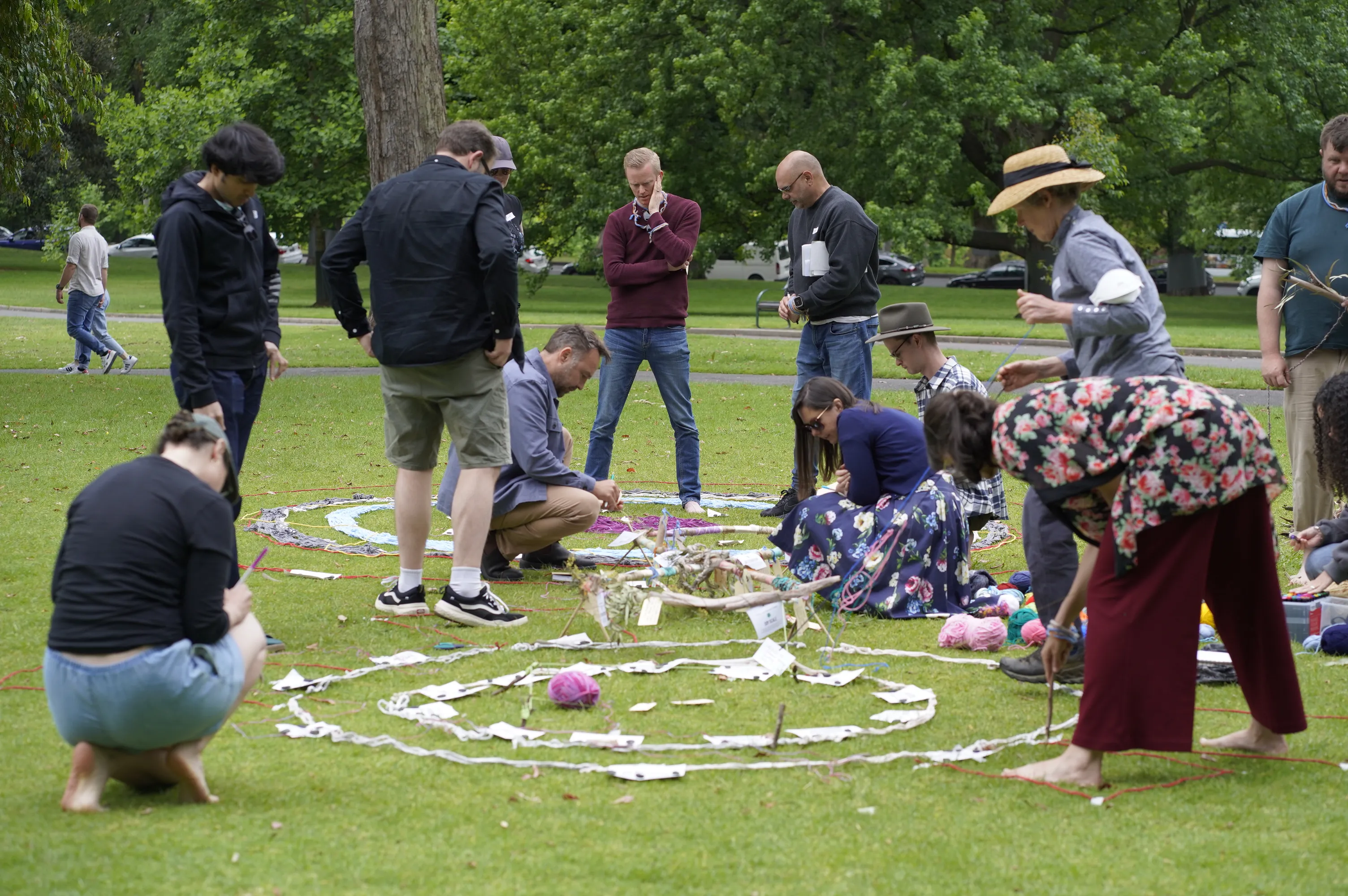 Participants collaboratively building a circular ground art installation in a Melbourne park