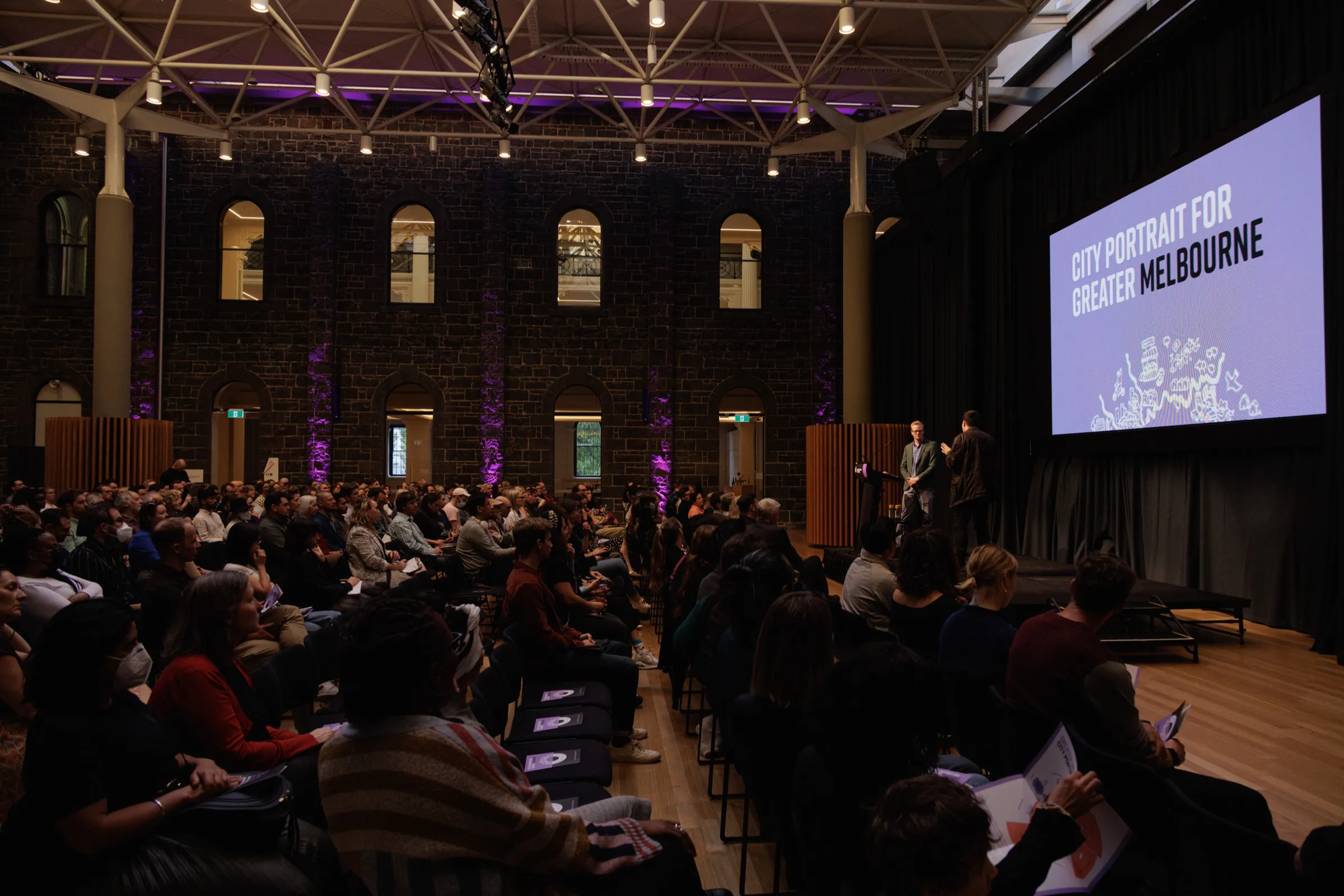 Large crowd at the City Portrait for Greater Melbourne launch in a heritage brick venue with purple lighting