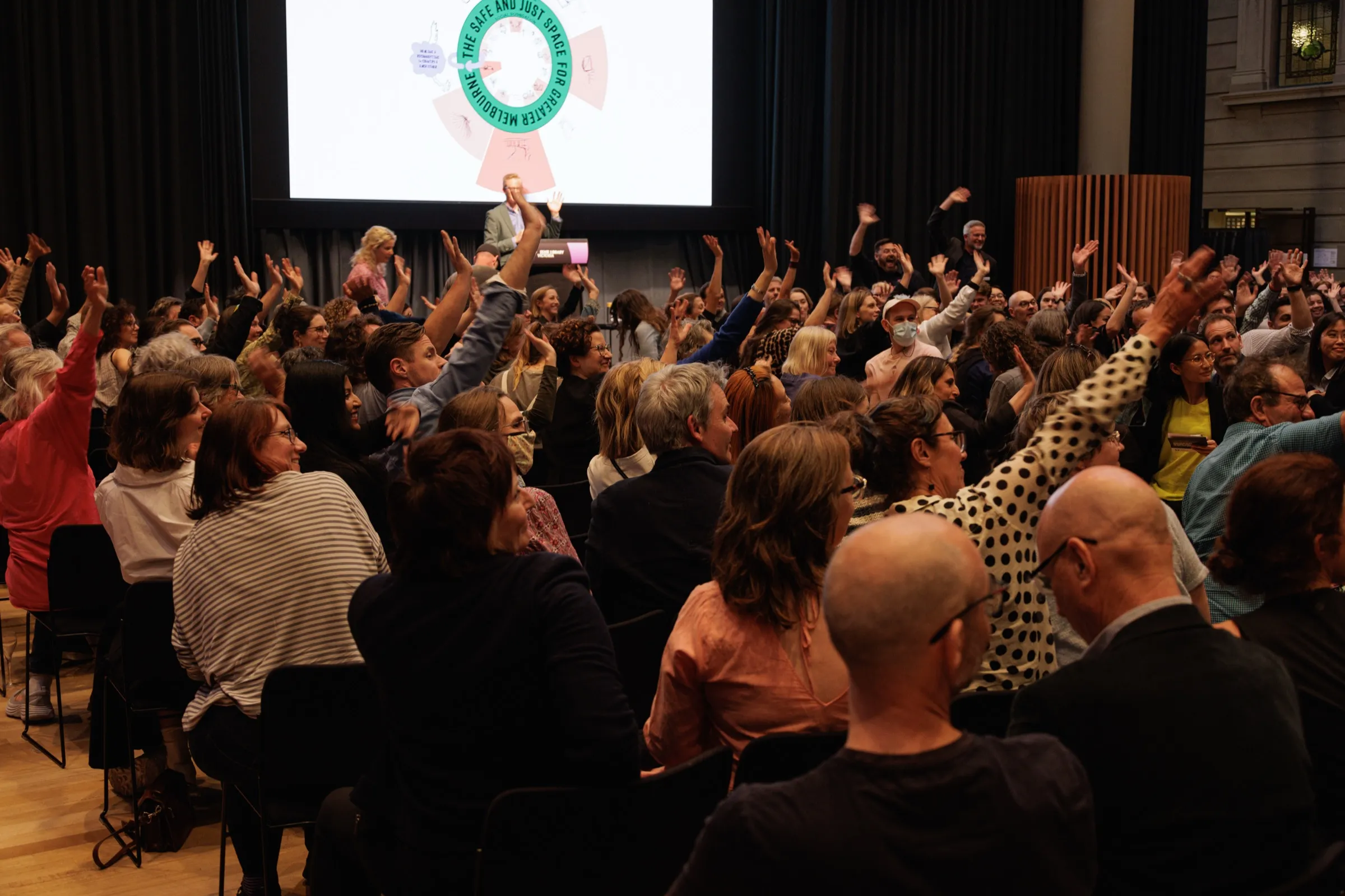 Enthusiastic audience with hands raised at the City Portrait for Greater Melbourne launch
