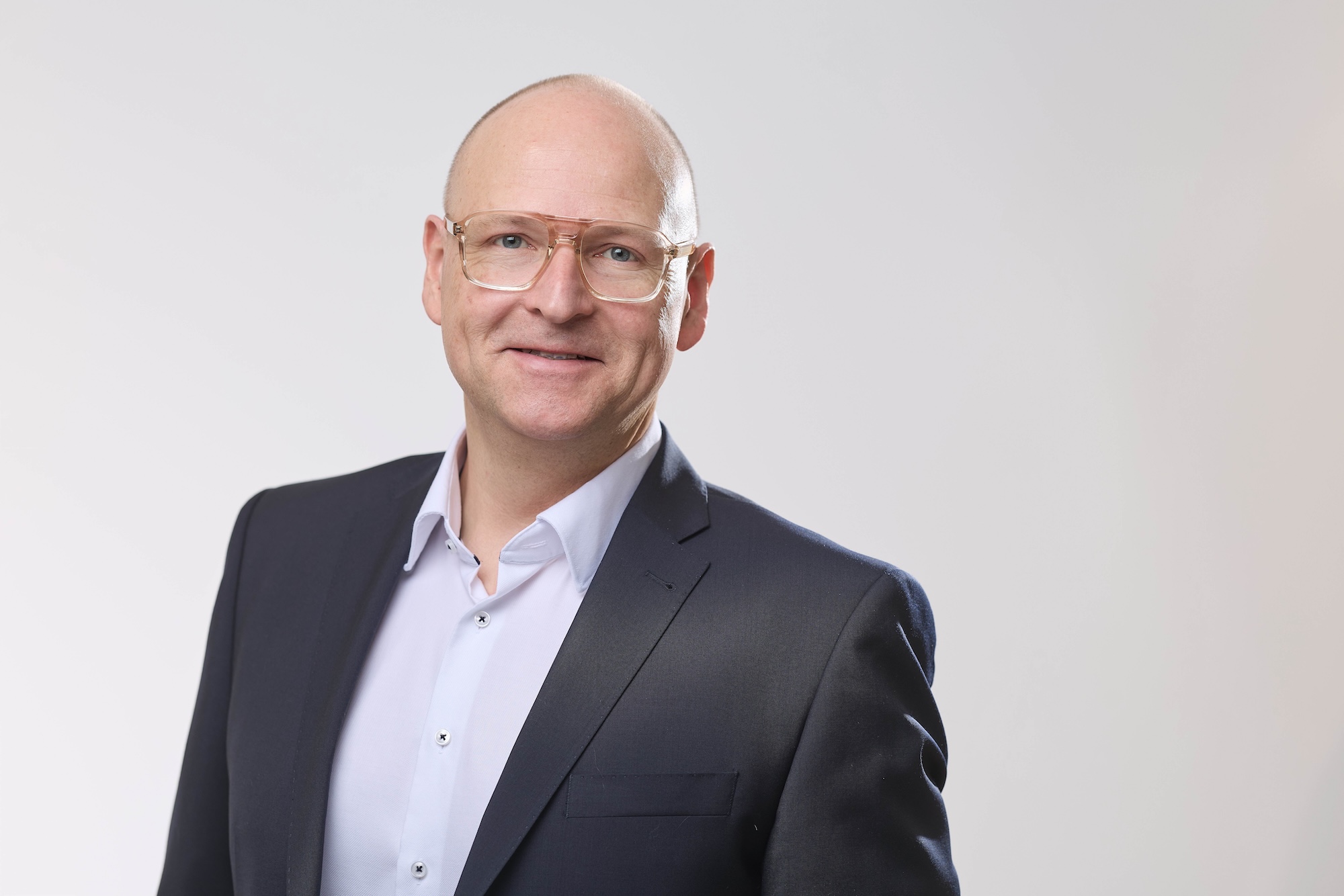 Porträt eines Mannes im dunklen Sakko vor hellem Hintergrund,