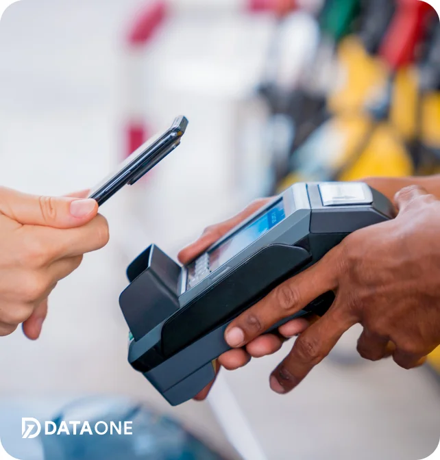 Close-up of a hand holding a smartphone near a payment terminal held by another hand, illustrating contactless mobile payment.