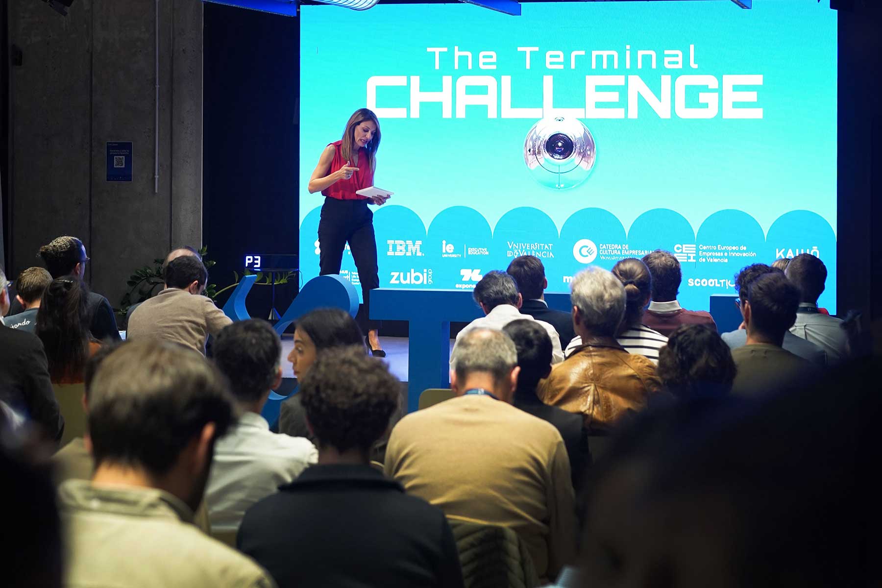 Mujer de pie presentando en un escenario frente a una audiencia durante The Terminal Challenge.