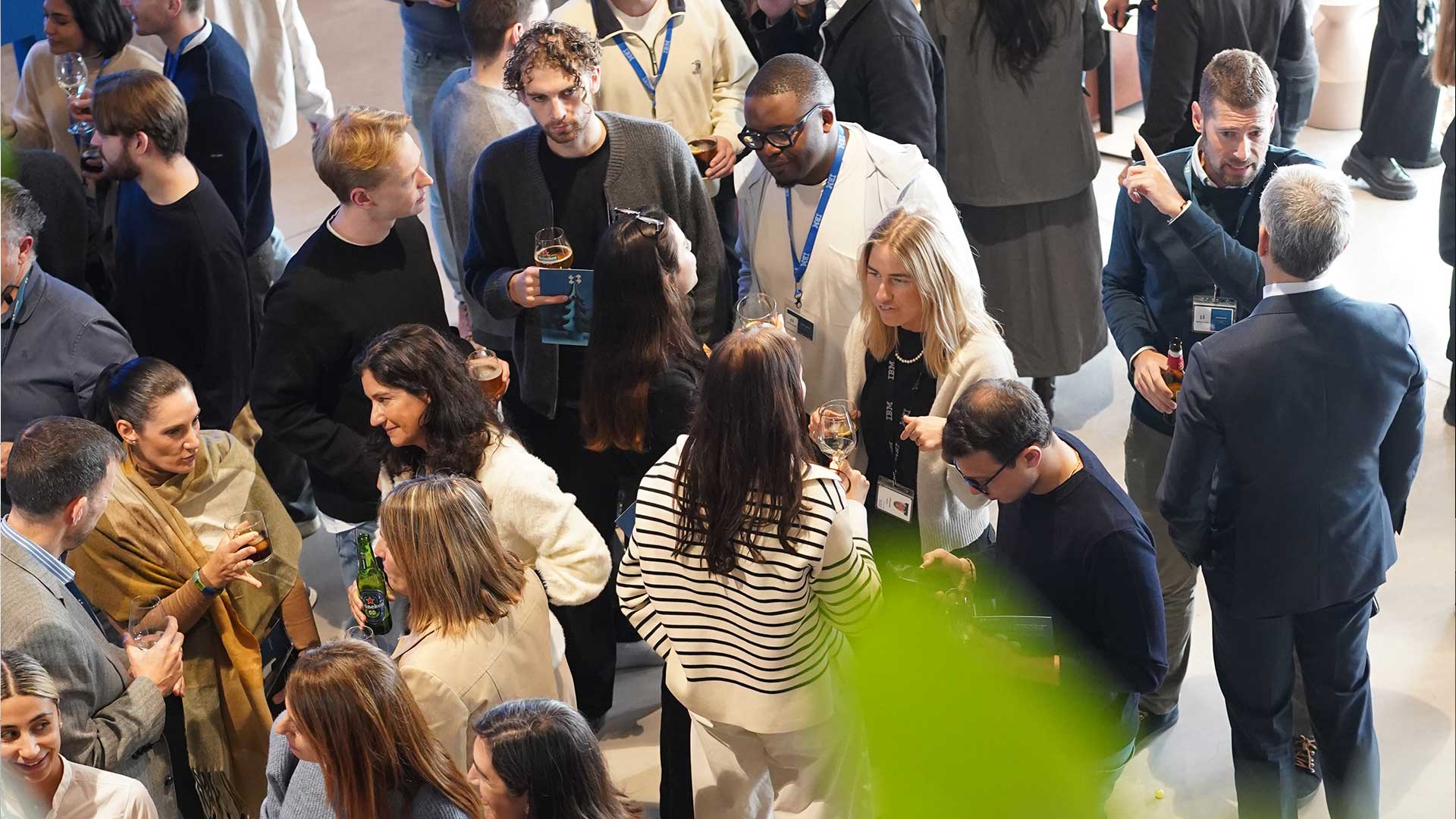 Grupo diverso de personas conversando en un evento social con bebidas en las manos.