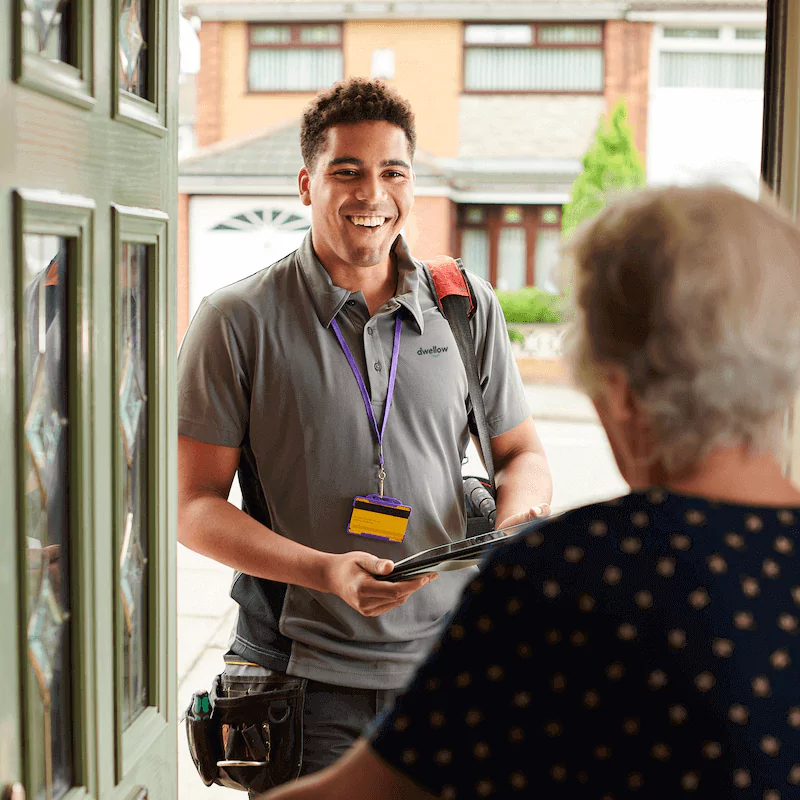 Dwellow heating engineer arriving at a customer's home being welcomed through the front door.