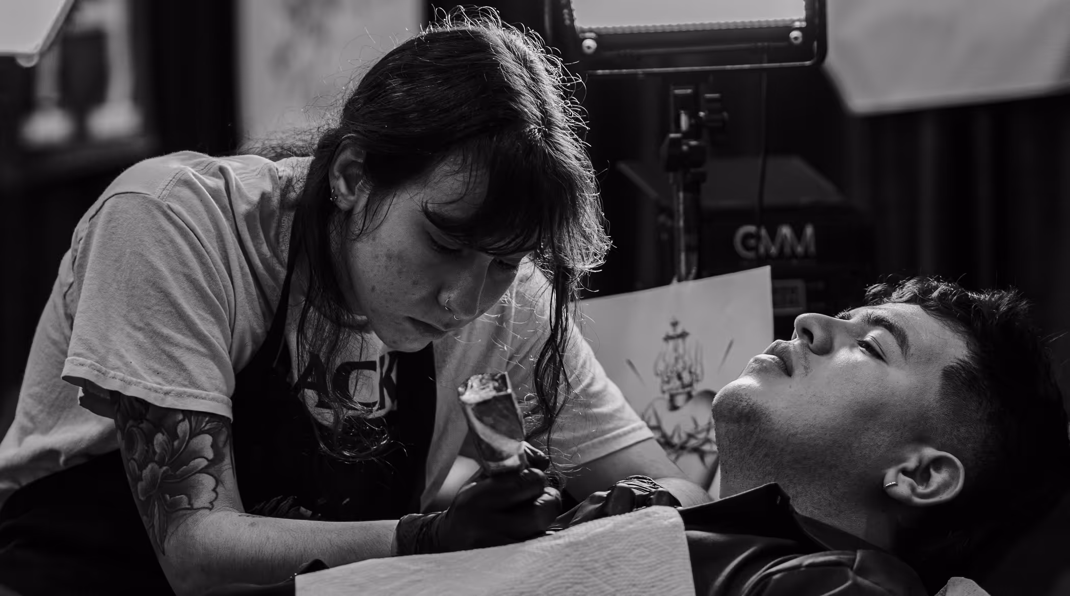 straight//line tattoo studio website hero — black and white photo of artist working on client