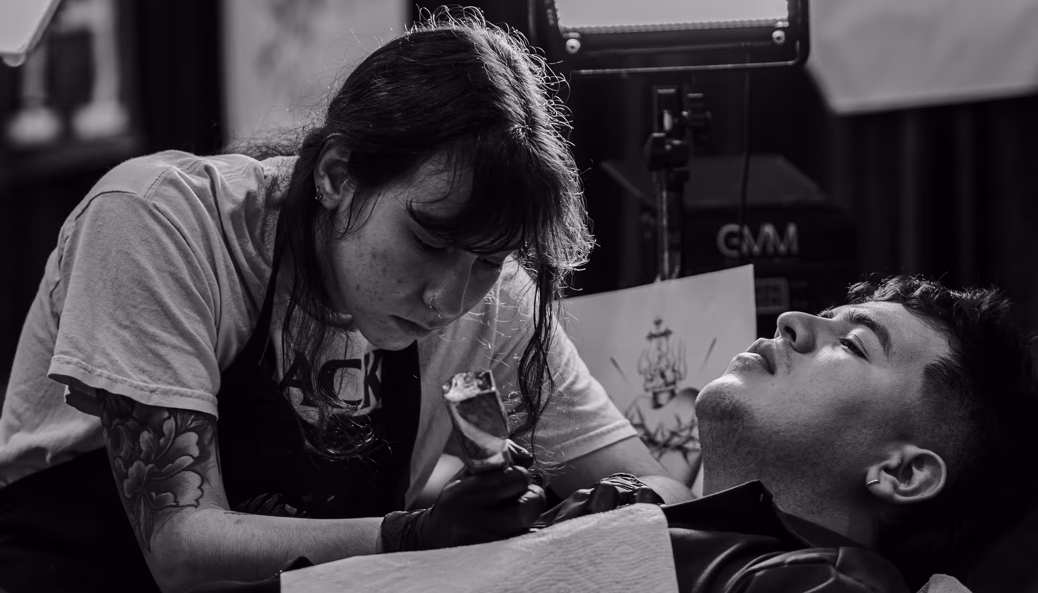straight//line tattoo studio website hero — black and white photo of artist working on client