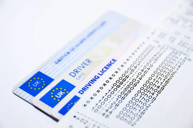 Close-up of UK driving licenses with category codes and validity dates.
