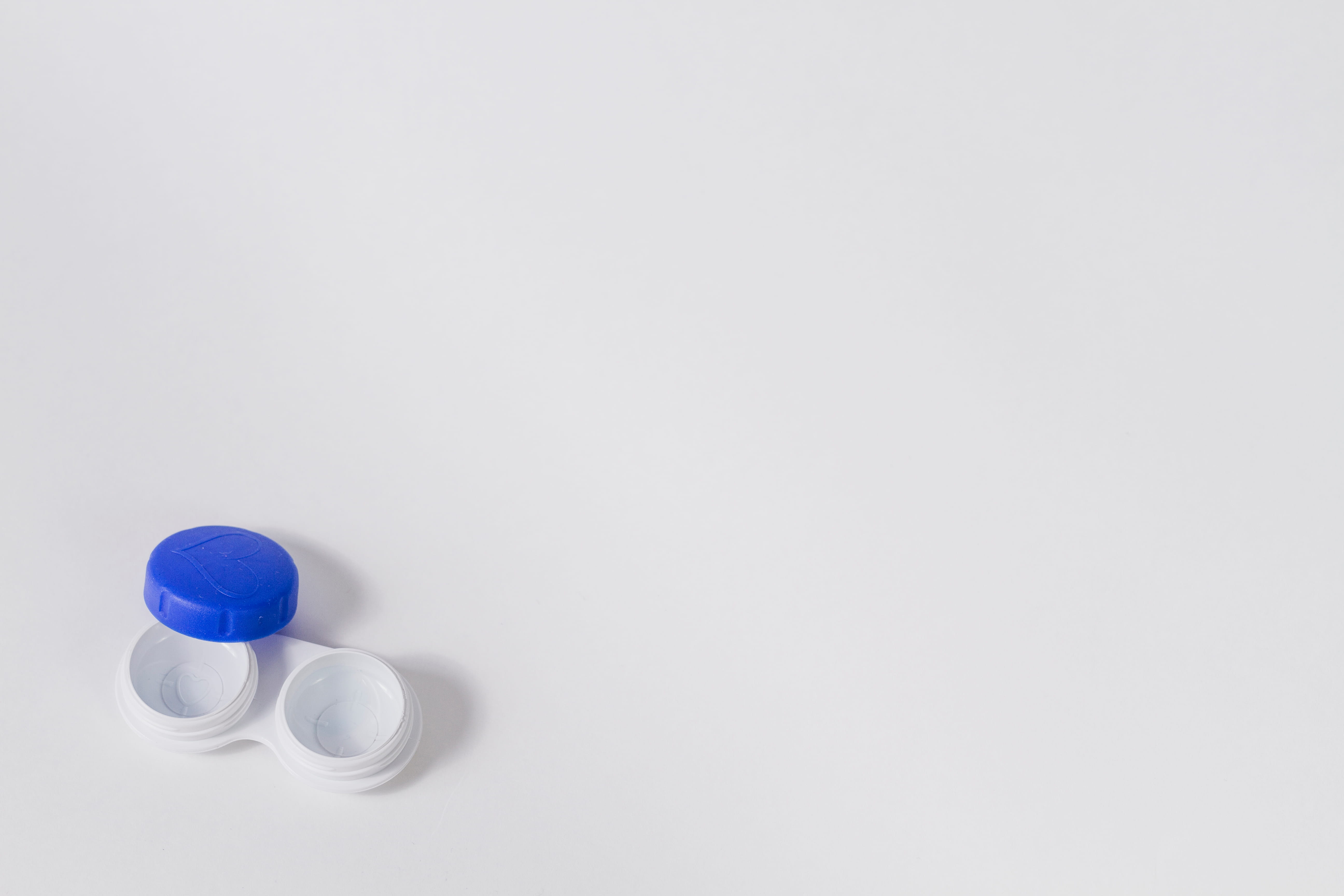 Contact lens case with blue lid and two white storage containers on white background