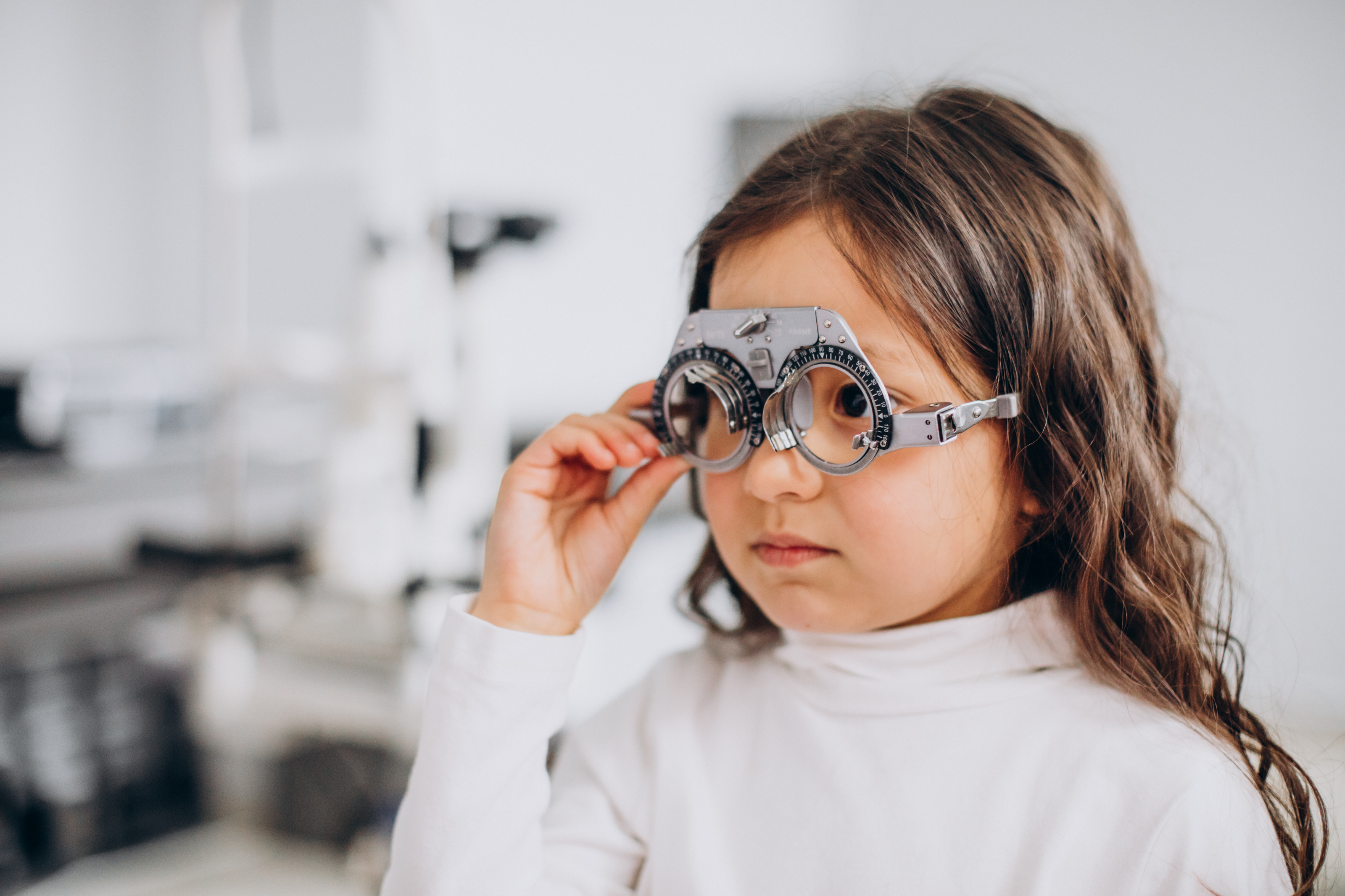 Child wearing optometric phoropter during eye exam in medical clinic