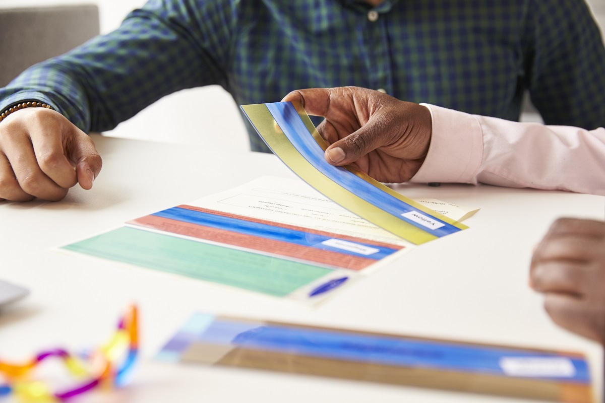 Person examining color swatch samples on white table during design consultation meeting