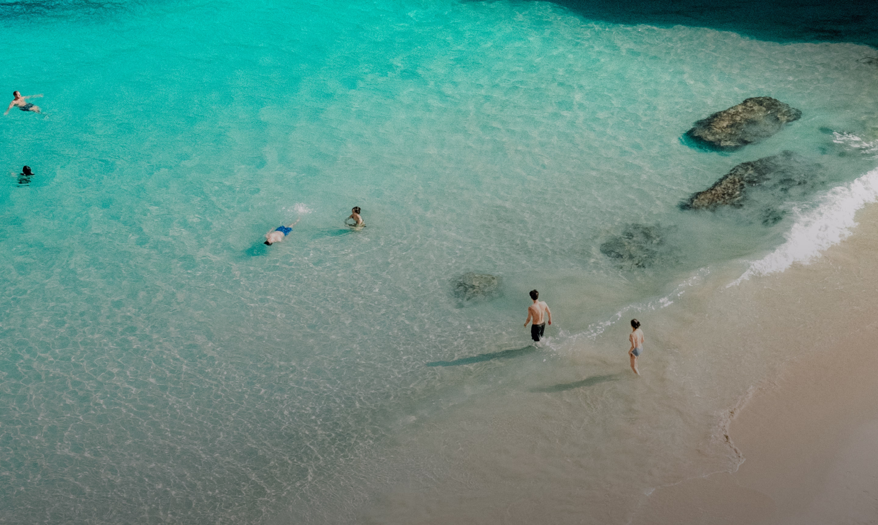 Aerial view of a turquoise Mallorca bay with swimmers wading near the shore