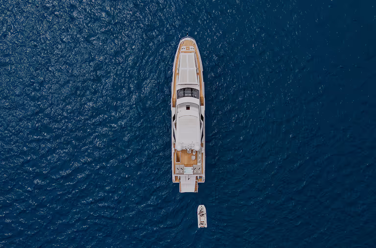 Aerial view of a sleek white yacht on deep-blue open water
