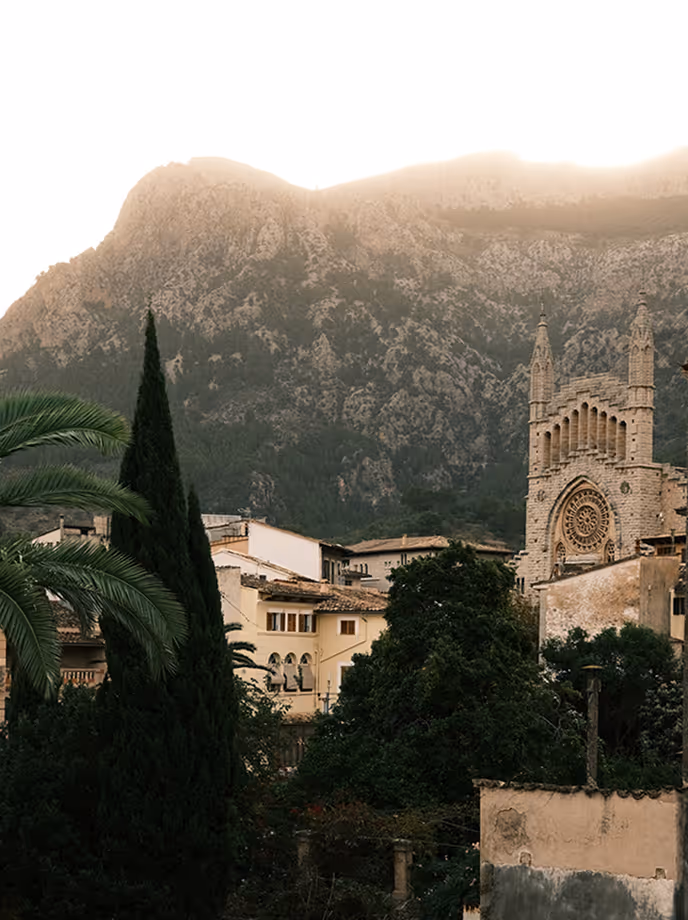 Misty Tramuntana mountain rising behind a village church and palms