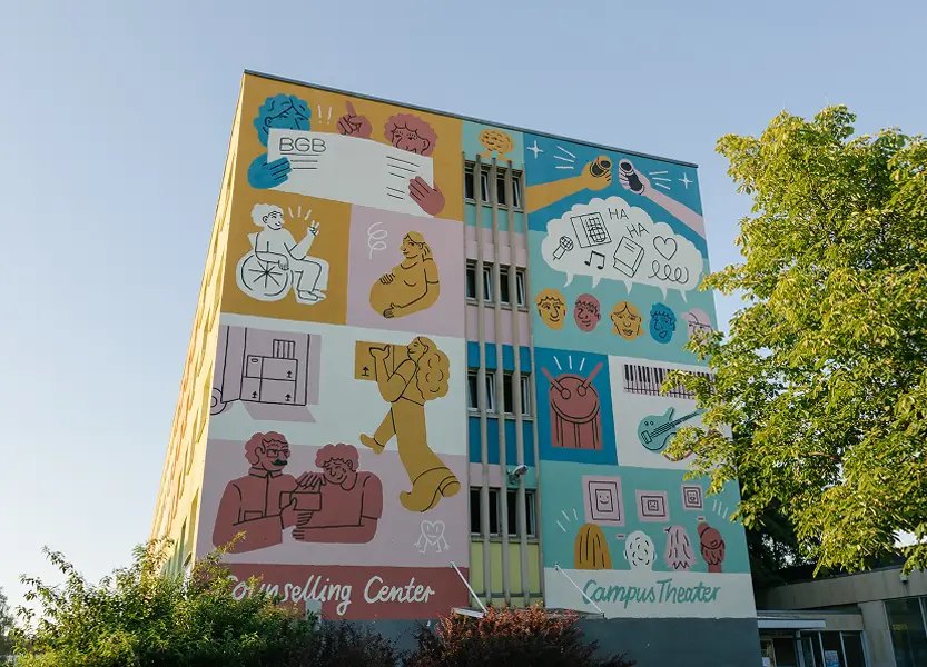 Das mehrstöckige Wohnheim nach der Fassadenbemalung mit bunten Illustrationen zu Themen wie Beratung, Theater und Musik.