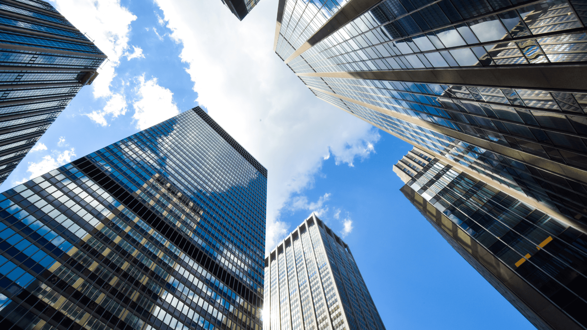 Vue en contre-plongée d'un ensemble de tours de bureaux en verre sur fond de ciel bleu