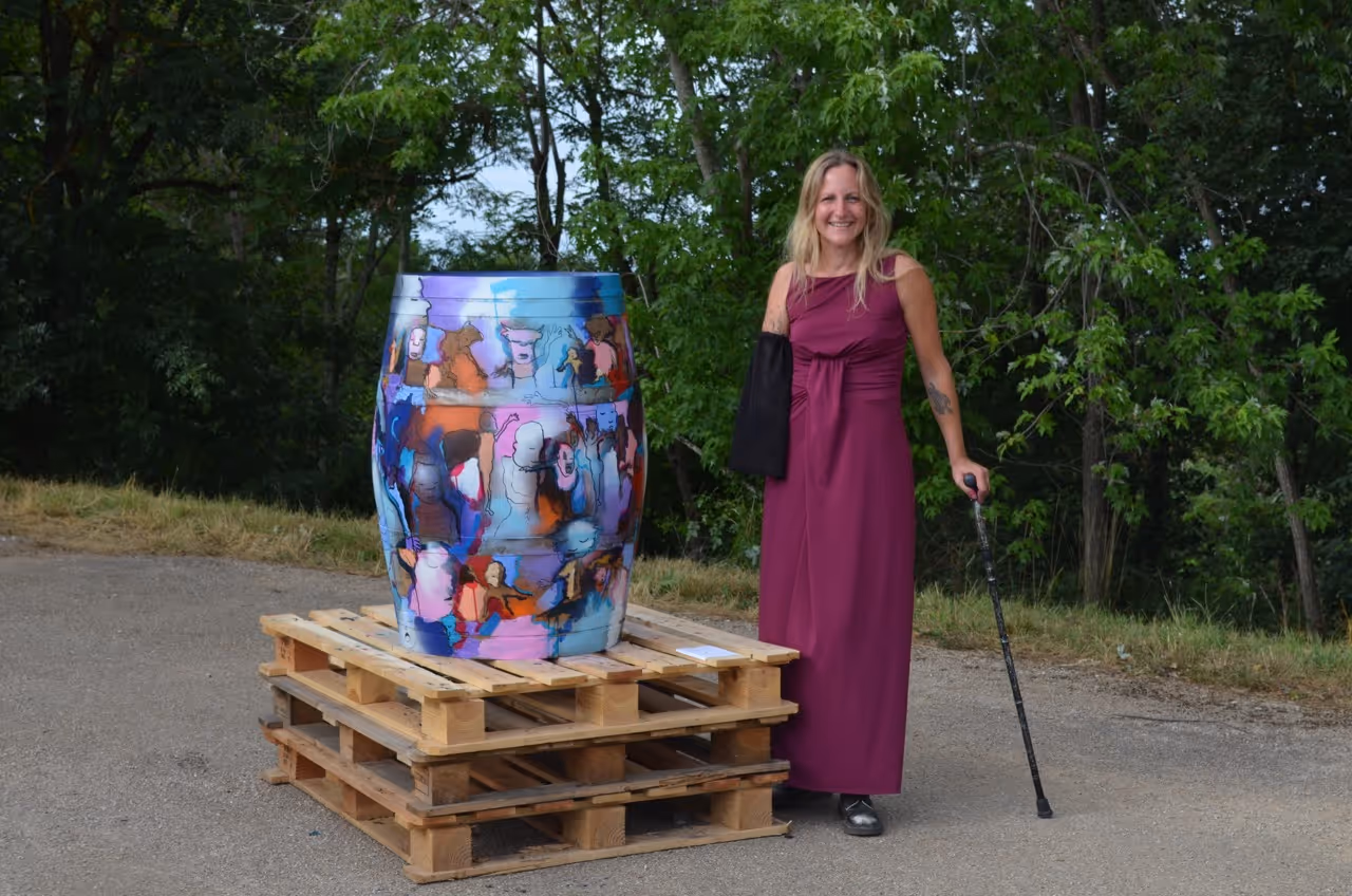 Femme posant devant une grande sculpture colorée en plein air, installation artistique