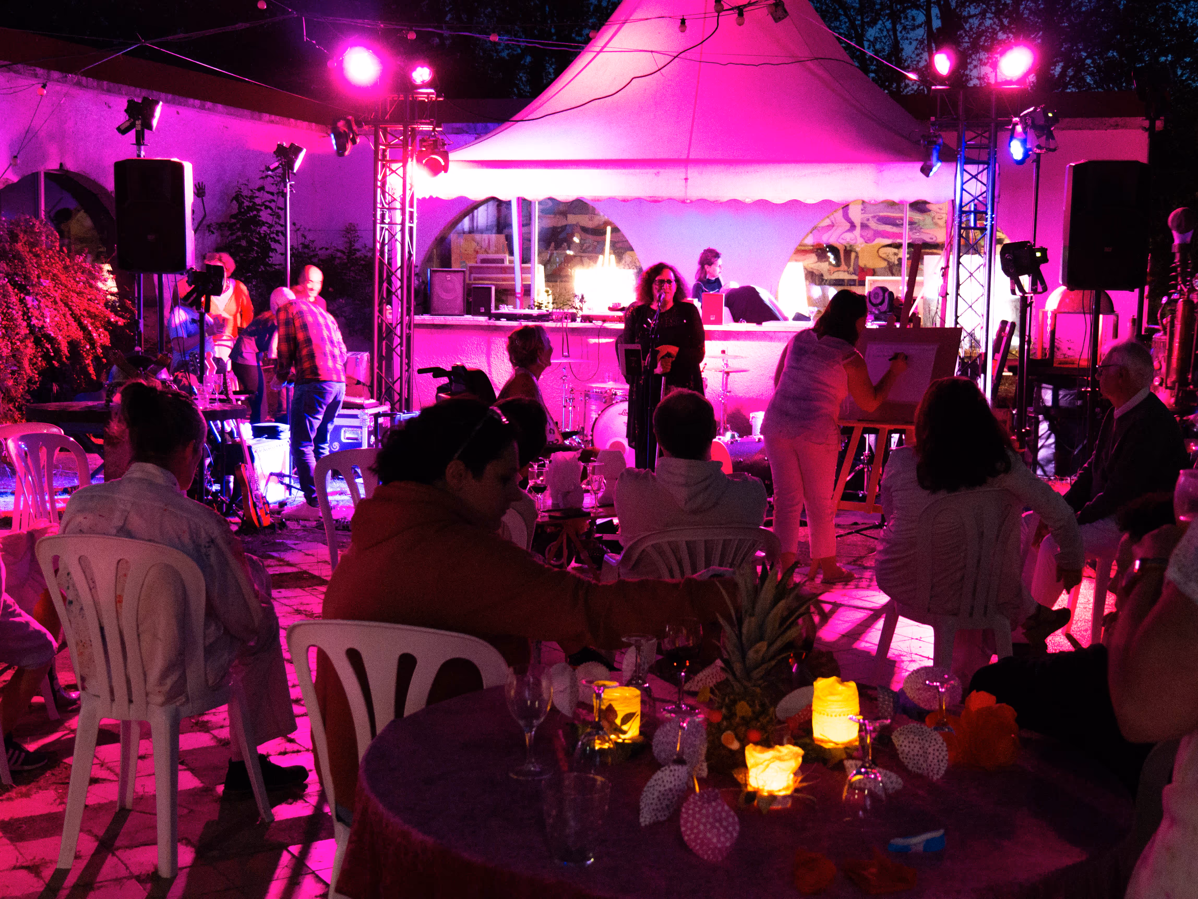 Ambiance festive lors d'un événement artistique avec des lumières roses et violettes et des participants