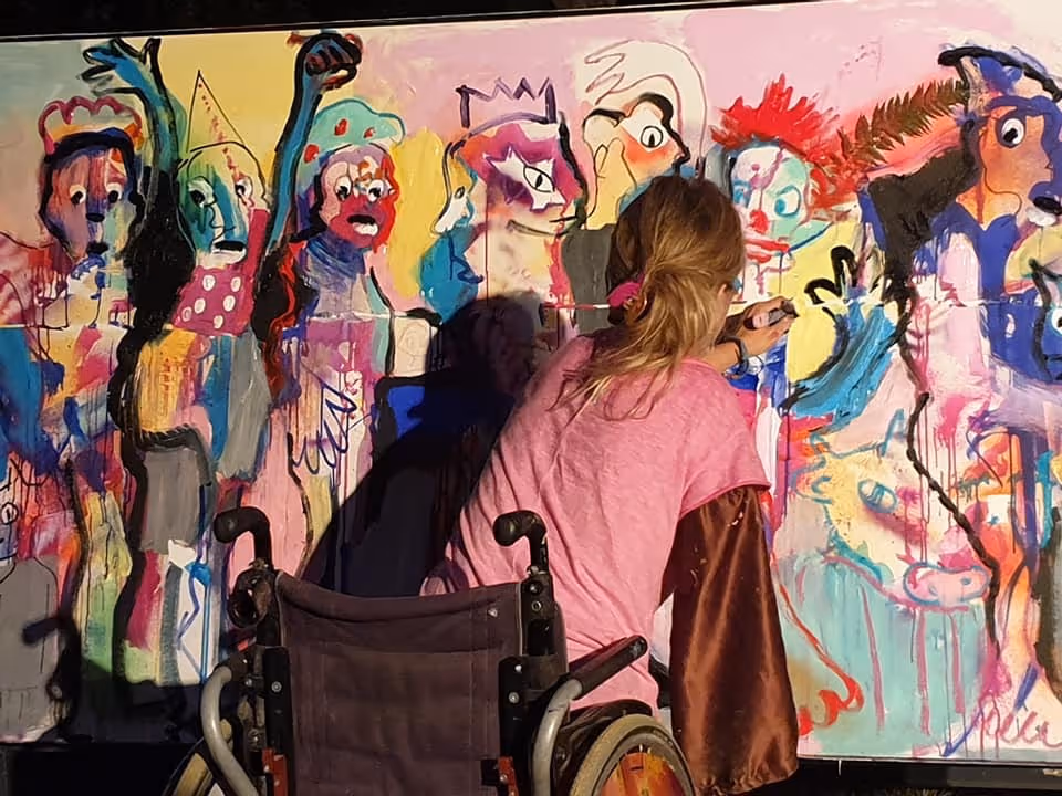 Participants d'un atelier de peinture créant ensemble une grande murale colorée avec des personnages festifs