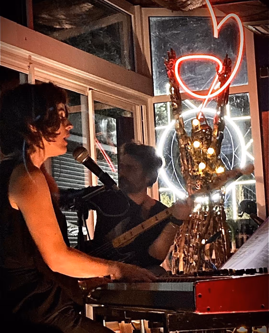 Musicienne jouant du piano lors d'un événement artistique avec un néon en forme de cœur en arrière-plan