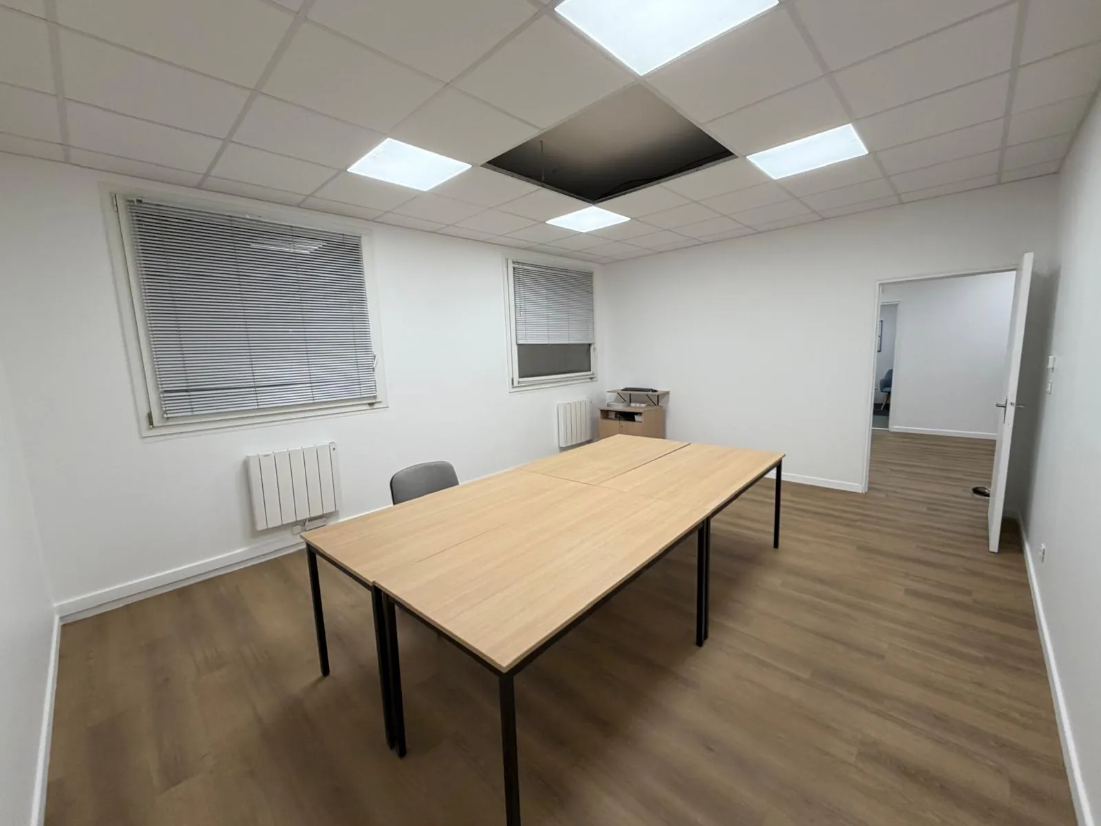 Bureau rénové avec parquet stratifié, faux plafond à dalles LED et stores vénitiens, aménagement professionnel clé en main