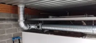 Gaines de ventilation en acier galvanisé installées sous plafond dans un local technique, réseau VMC