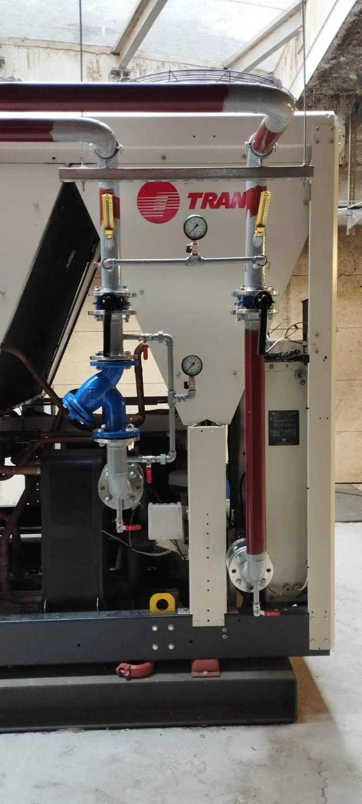 Groupe froid industriel Trane installé en local technique avec manomètres, vannes et raccordements hydrauliques