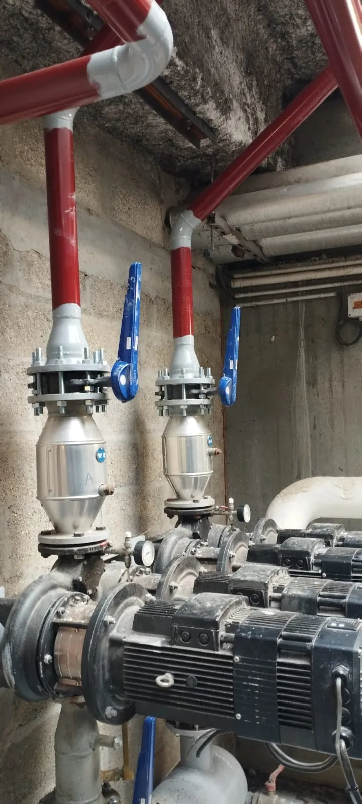 Local technique avec pompes de circulation, vannes papillon à levier bleu et canalisations rouges pour système de climatisation