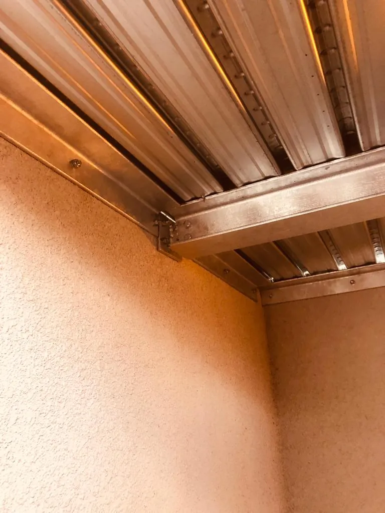 Sous-face de la mezzanine métallique avec tôle nervurée galvanisée fixée aux poutres et ancrée au mur